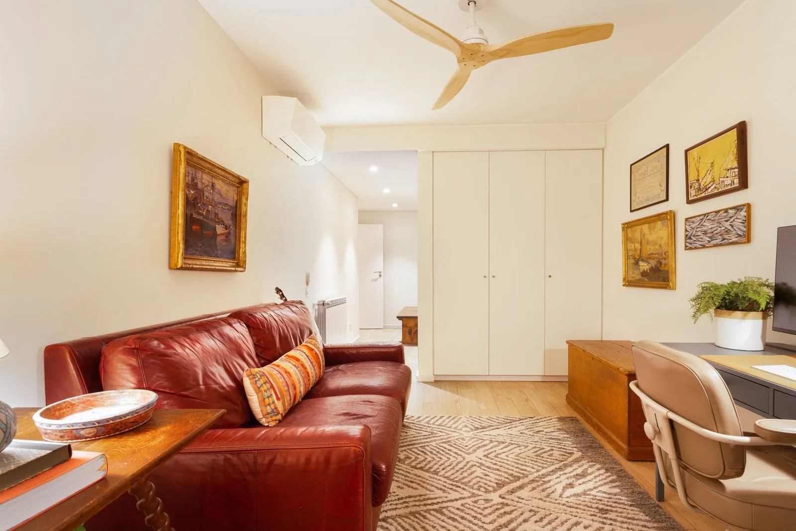 Escritório com sofá em pele vermelha e arrumação embutida — moradia Riviera Cascais pela Maya's Homes