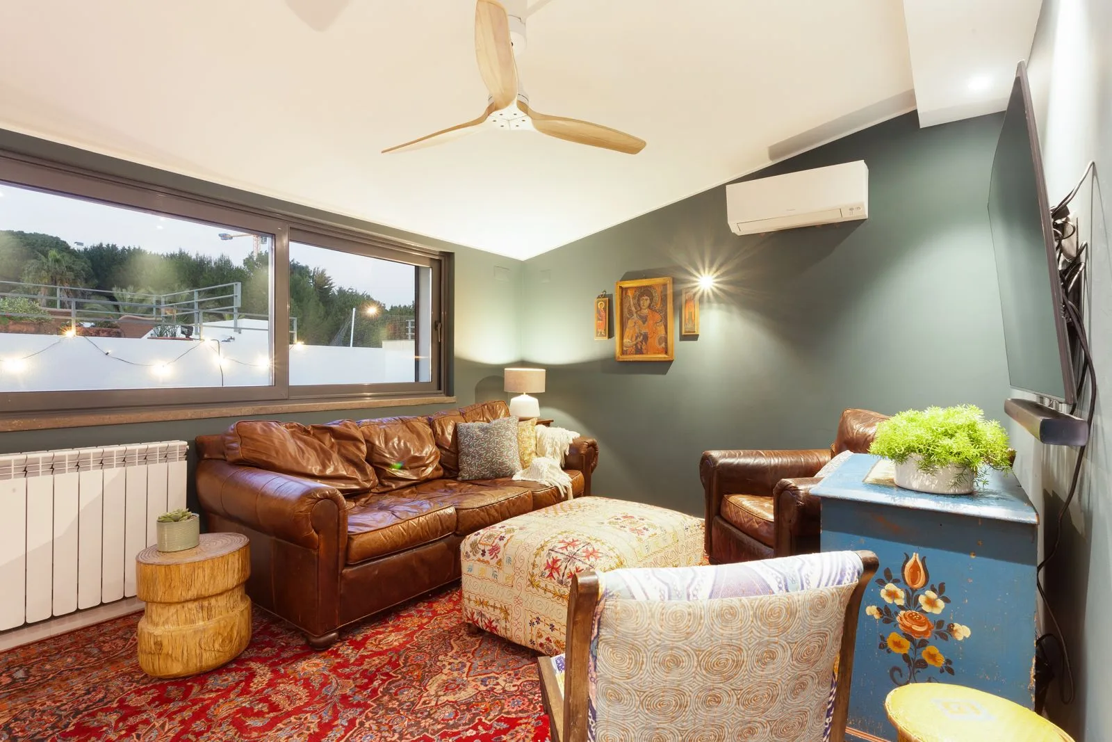 Segundo salão com parede verde e sofá em pele — renovação moradia Riviera Cascais pela Maya's Homes