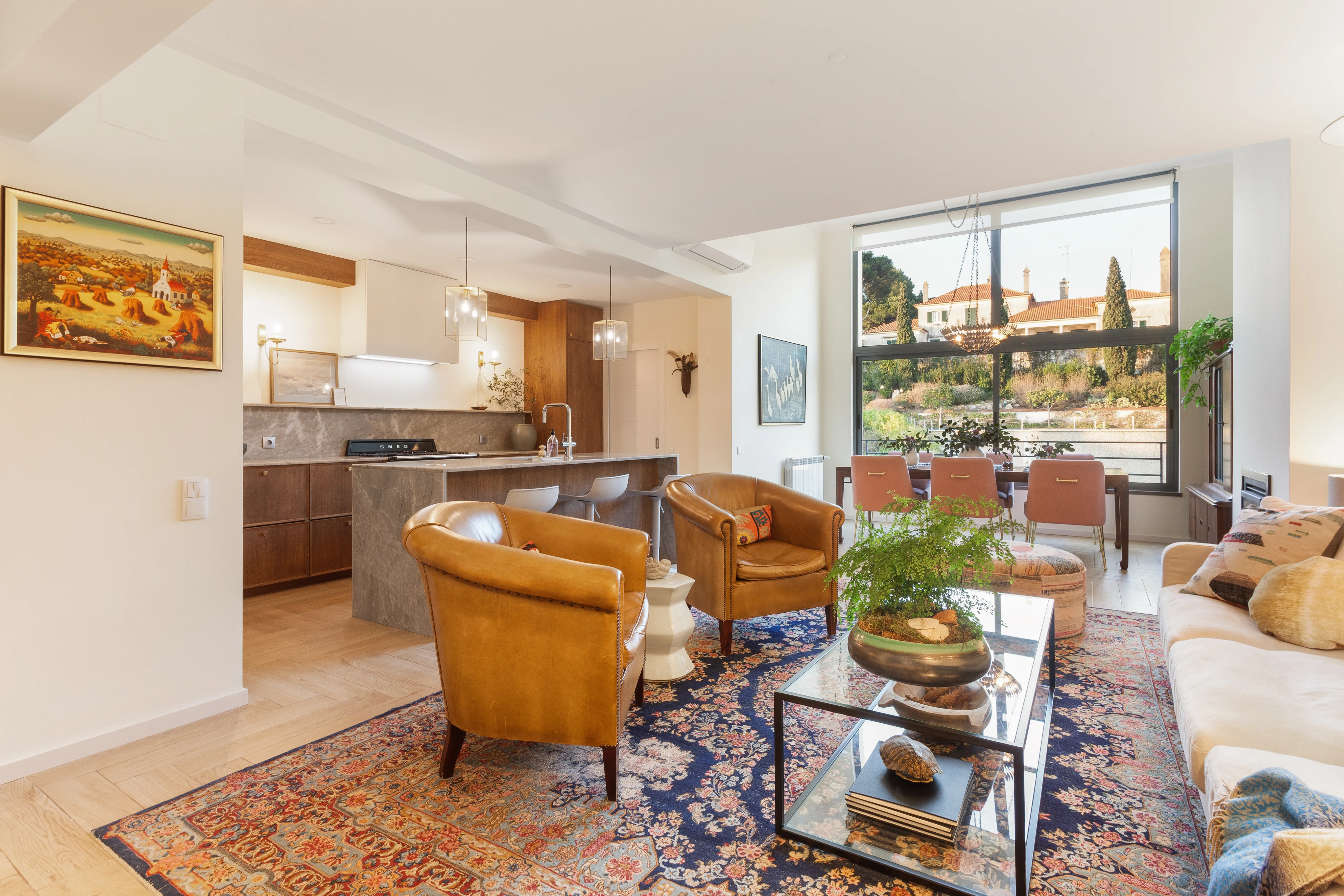 Sala open-plan com poltronas em pele e tapete persa — renovação moradia Riviera Cascais pela Maya's Homes