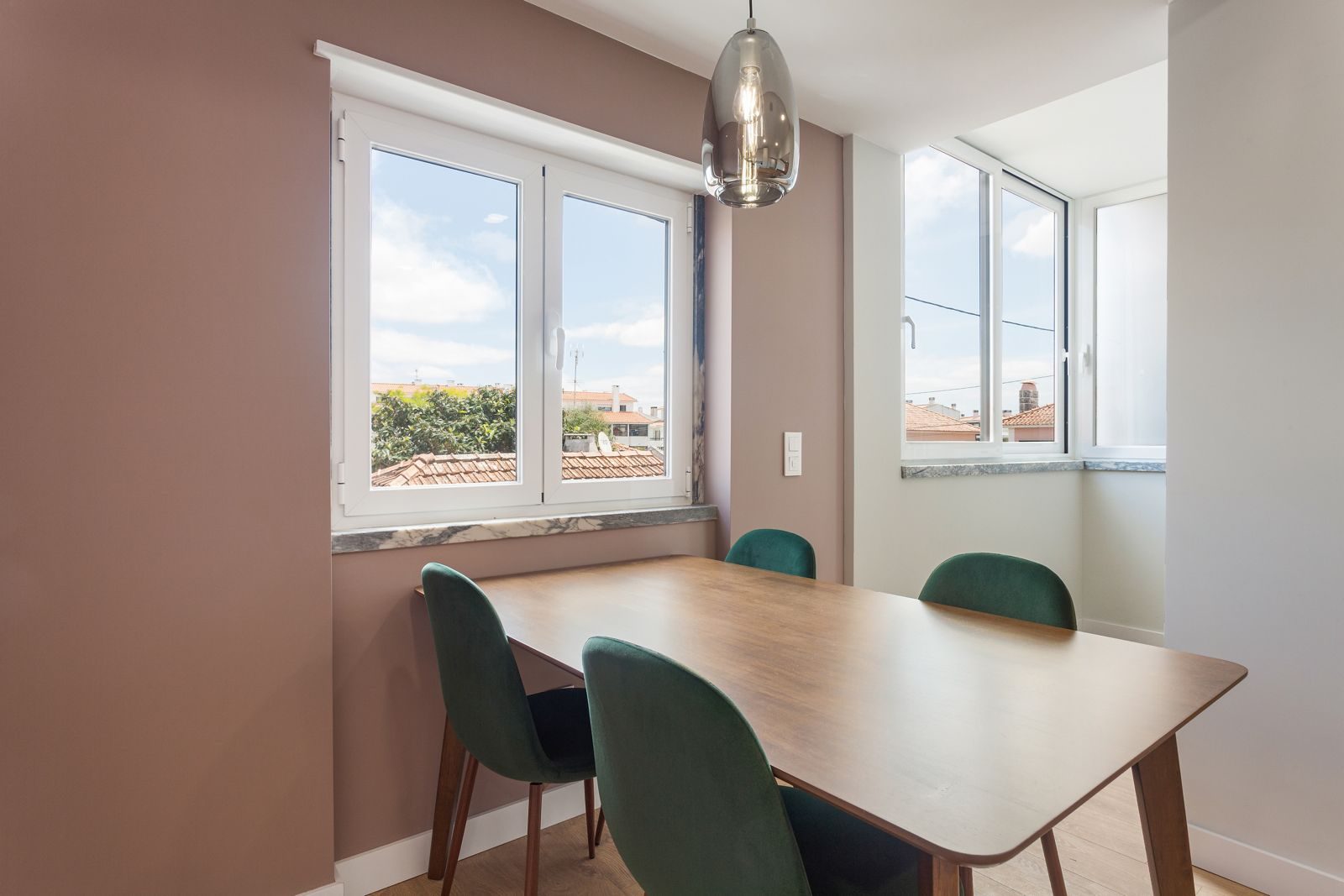 Dining area with green velvet chairs and mauve wall